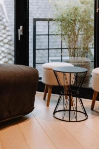 d'un salon avec une table, des chaises et une fenêtre. dans l'établissement Chimay : La Chambre Dorée de la Grand Place, à Chimay