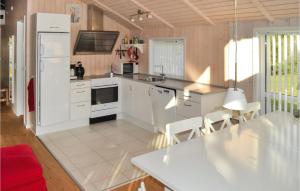 cocina con armarios blancos y nevera blanca en Cozy Home In Sby With Wifi en Nordost
