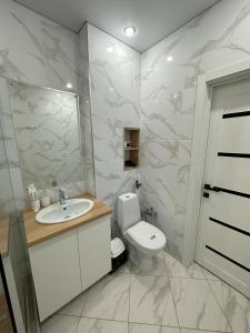 ein Badezimmer mit einem WC, einem Waschbecken und einem Spiegel in der Unterkunft Apart Inn - Апарт Отель in Oral