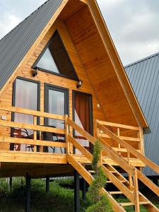 a cabin with a gambrel roof and a large deck at Panorama Dashbashi - Hotel in Dashbashi