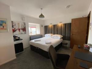 a bedroom with a large bed and a desk at The Crossroads Inn in Sacriston