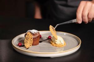 una persona comiendo un postre en un plato con un tenedor en Hotel Costes, en Corvara in Badia