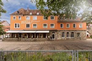 ein großes orangenes Hotel mit einem Zaun davor in der Unterkunft Ferienwohnung Fischzucht - Sauna, große Dachterrasse, 3 Schlafzimmer - by homekeepers in Würzburg