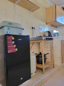 a kitchen with a black refrigerator and a sink at Rozy homes Jinja in Jinja