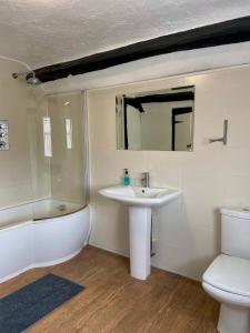 uma casa de banho com um lavatório, uma banheira e um WC. em The King's Lodge Hotel em Kings Langley