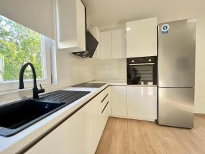La cuisine blanche est équipée d'un évier et d'un réfrigérateur. dans l'établissement Brand new, 1 bedroom apartment Poreč, à Poreč