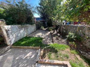 a garden with a stone wall and a sidewalk at Littlehampton House - 4 bedroom house sleeps 8 in Littlehampton