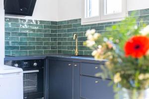 uma cozinha com um lavatório e uma parede de azulejos verdes em Appartement avec terrasse proche Panier em Marselha