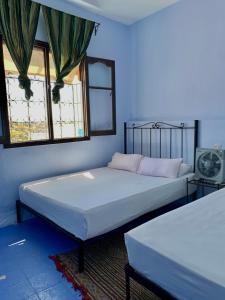 two beds in a room with two windows at Dar Besmellah in Chefchaouen