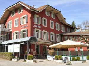 ein großes rotes Gebäude mit einem Schirm davor in der Unterkunft ZIEGELHÜSI Hotel, Stettlen bei Bern in Bern