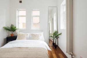 una camera da letto con pareti bianche e un letto bianco con cuscini di Modern 1BD Flat -Stoke Newington a Londra