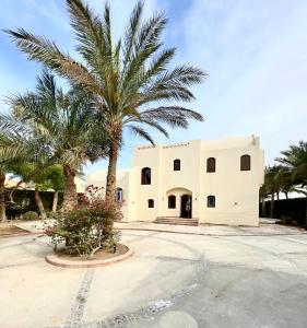 a building with a palm tree in front of it at BEAUTIFUL 4-BEDROOM VILLA WITH POOL AND VIEWS OF THE LAGOON AND GOLF COURSE in Hurghada