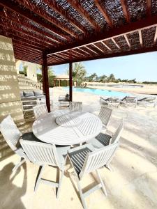 a patio with a table and chairs and a pool at BEAUTIFUL 4-BEDROOM VILLA WITH POOL AND VIEWS OF THE LAGOON AND GOLF COURSE -minimum stay of 4 nights in Hurghada