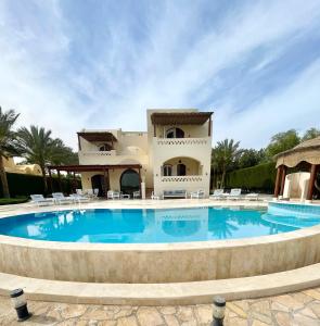 a large swimming pool in front of a villa at BEAUTIFUL 4-BEDROOM VILLA WITH POOL AND VIEWS OF THE LAGOON AND GOLF COURSE in Hurghada
