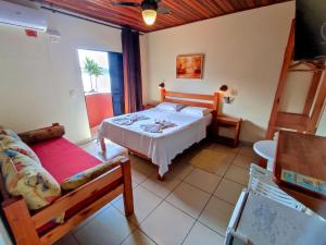 a bedroom with a bed and a couch in a room at Pousada Casa na Praia in Ubatuba