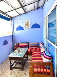 una stanza con divani, tavolo e panca di Dar Besmellah a Chefchaouen