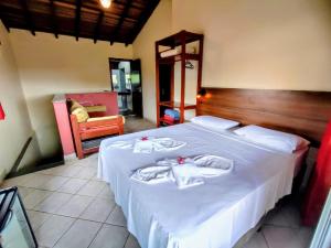 um quarto com uma cama branca e toalhas em Pousada Casa na Praia em Ubatuba