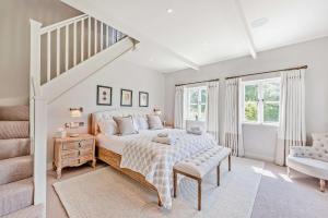 a white bedroom with a bed and a staircase at Bedgebury Oast by Bloom Stays in Goudhurst