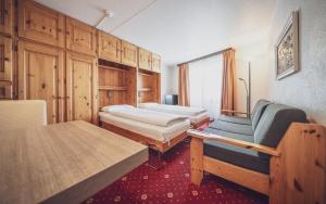 Zimmer mit 2 Betten, einem Tisch und einem Stuhl in der Unterkunft Club Hotel Davos by Mountain Hotels in Davos