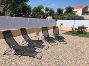 quatro cadeiras pretas e uma mesa num quintal em Villa - Saint Cyprien em Théza