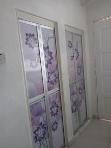Cette chambre dispose de deux portes vitrées avec des fleurs violettes. dans l'établissement SERI BAKAWALI HOMESTAY, à Rawang