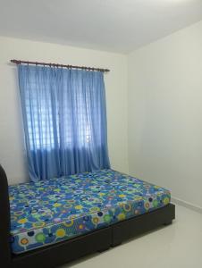 1 dormitorio con 1 cama con cortina azul en SERI BAKAWALI HOMESTAY en Rawang