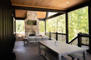 um alpendre coberto com uma lareira de pedra e uma mesa em NEW Creek Side, Luxury Cabin – Willow Creek em Stephens Gap