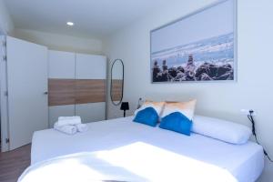 a bedroom with a large white bed with blue pillows at BILBAO NORTH SHORE APARTMENTS in Bilbao