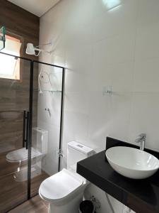 La salle de bains blanche est pourvue d'un lavabo et de toilettes. dans l'établissement Hotel Chão Mineiro, à São Thomé das Letras