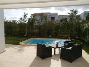 uma piscina com cadeiras e uma mesa num quintal em Villa 280 m2 à Benslimane avec piscine em Aïn Sferjila