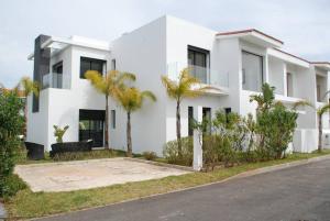 uma casa branca com palmeiras em frente em Villa 280 m2 à Benslimane avec piscine em Aïn Sferjila
