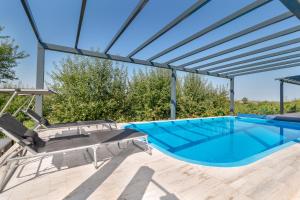 a swimming pool with a pergola and patio furniture at Casa Fischer in Ciheiu