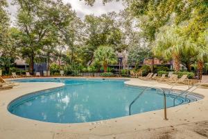 a swimming pool with lounge chairs and trees at Turnberry Village 291 in Hilton Head Island