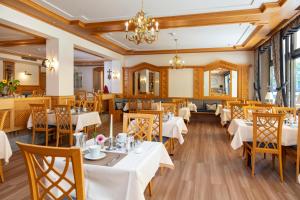 restauracja z białymi stołami i krzesłami oraz żyrandolem w obiekcie Parkhotel an der Therme w mieście Bad Krozingen