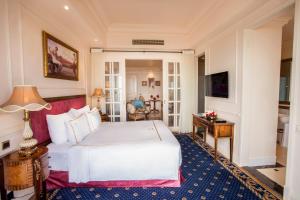 a bedroom with a large white bed and a table at The IMPERIAL Vung Tau Hotel in Vung Tau