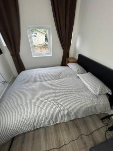 ein großes Bett in einem Schlafzimmer mit Fenster in der Unterkunft Large studio flat with garden in Teddington