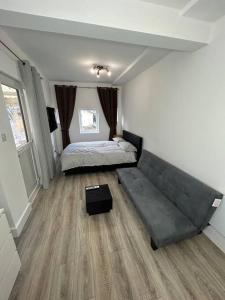 a bedroom with a bed and a couch in it at Large studio flat with garden in Teddington