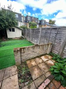 a backyard with a fence and a yard withgrass at Large studio flat with garden in Teddington