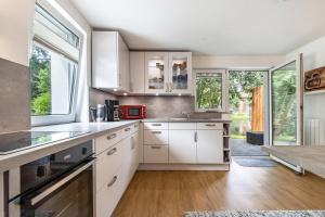 a kitchen with white cabinets and wood floors and windows at Ferienwohnung am Parksee in Bad Bodenteich