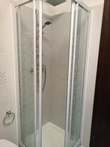 una ducha con puerta de cristal en un baño en margue residence meledrio, en Folgarida