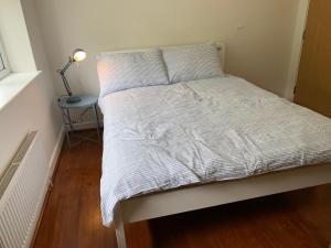Ce lit se trouve dans un dortoir doté d'une lampe sur une table. dans l'établissement Wokingham - Large 2 bedroom Apartment, à Wokingham