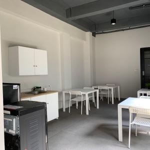 a kitchen with white tables and chairs and white cabinets at PassGo Thamrin in Jakarta