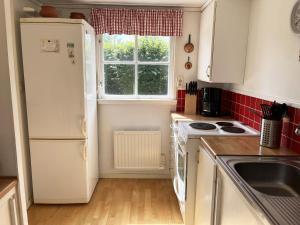 une cuisine avec un réfrigérateur blanc et une fenêtre dans l'établissement Cozy cottage close to Farjestaden, à Färjestaden