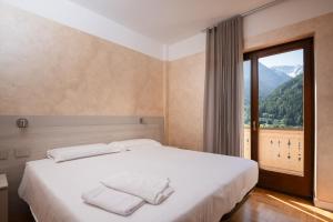 a bedroom with a bed and a large window at Hotel Vezza Alpine Lodge & Spa in Vezza dʼOglio