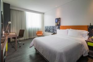 een hotelkamer met een groot bed en een bureau bij Hampton by Hilton Barranquilla in Barranquilla