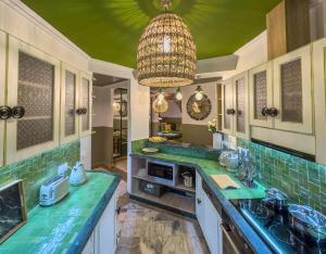 una cocina con encimeras verdes y una lámpara de araña en Maison Maria Palmeraie, en Marrakech