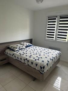 een slaapkamer met een bed in een witte kamer bij Chez Greg et Laëtitia2 