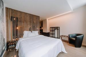 1 dormitorio con 1 cama blanca grande y 1 silla en Chimay : La Chambre Bleue de la Grand Place, en Chimay