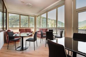 a restaurant with tables and chairs and windows at Hotel Vezza Alpine Lodge & Spa in Vezza dʼOglio