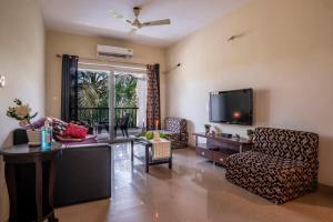 a living room with a tv and a chair and a table at Goa Chillout Apartment - 1BHK, Baga in Baga